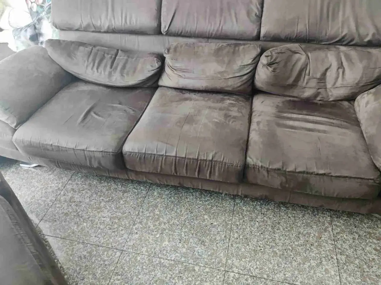 Divano marrone con cuscini un po' affossati, pronti per rifare imbottitura cuscini divano e ridargli vita.
