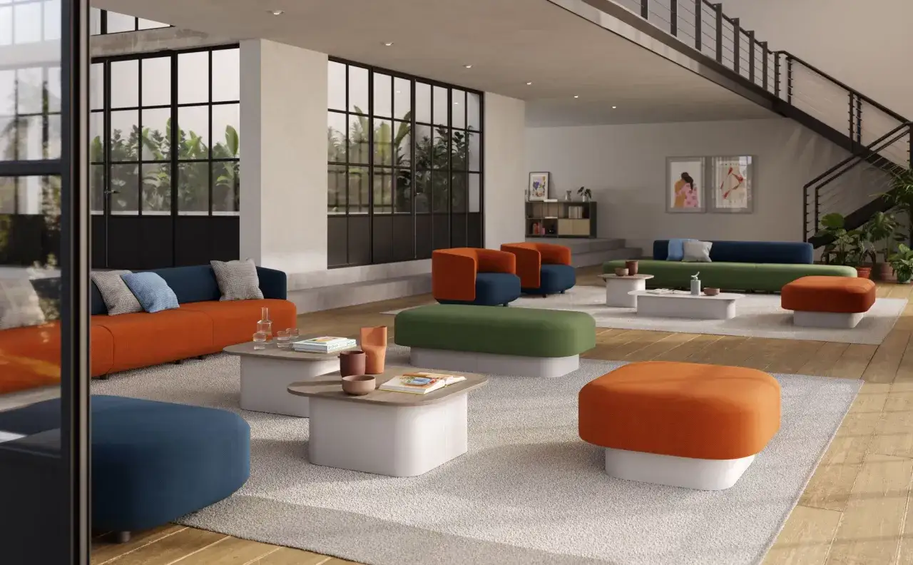 Un salotto moderno con divani e pouf dal design audace, in arancione, blu e verde, su un tappeto chiaro.