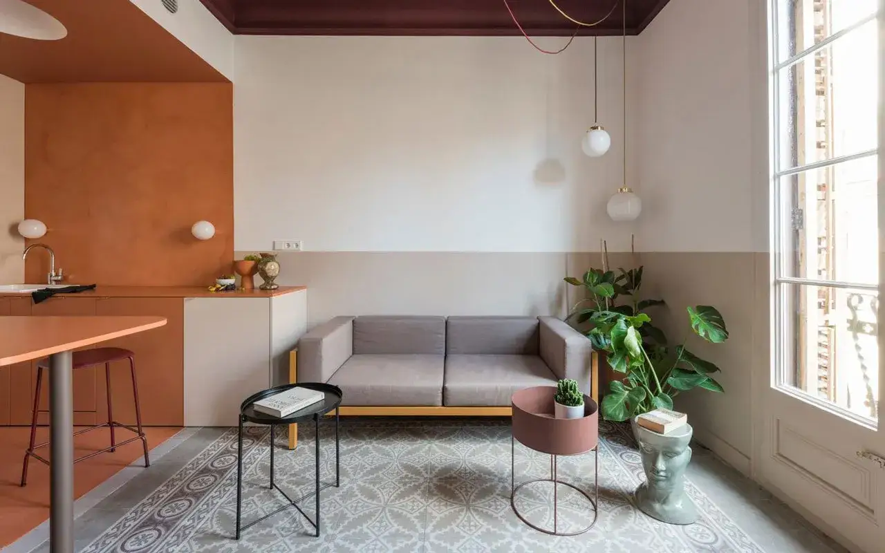 Soggiorno moderno con cucina a vista, divano grigio, tavolini e piante. Idee boiserie soggiorno con pareti colorate e dettagli di design.