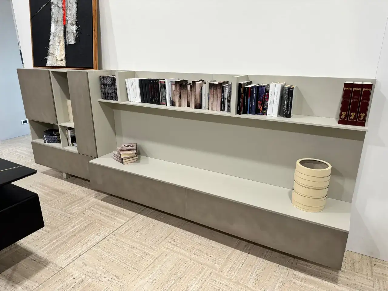 Elegante lema parete attrezzata con libreria a giorno, vani chiusi e un quadro astratto.