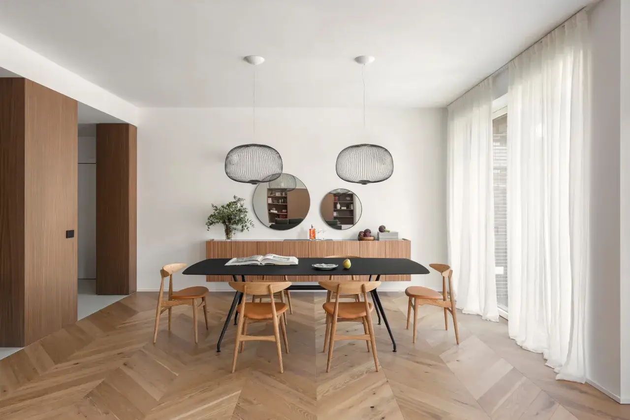 Un'elegante sala da pranzo con un tavolo nero, sedie in legno e un mobile a parete. L'ambiente è perfetto per arredare sala da pranzo con stile moderno.