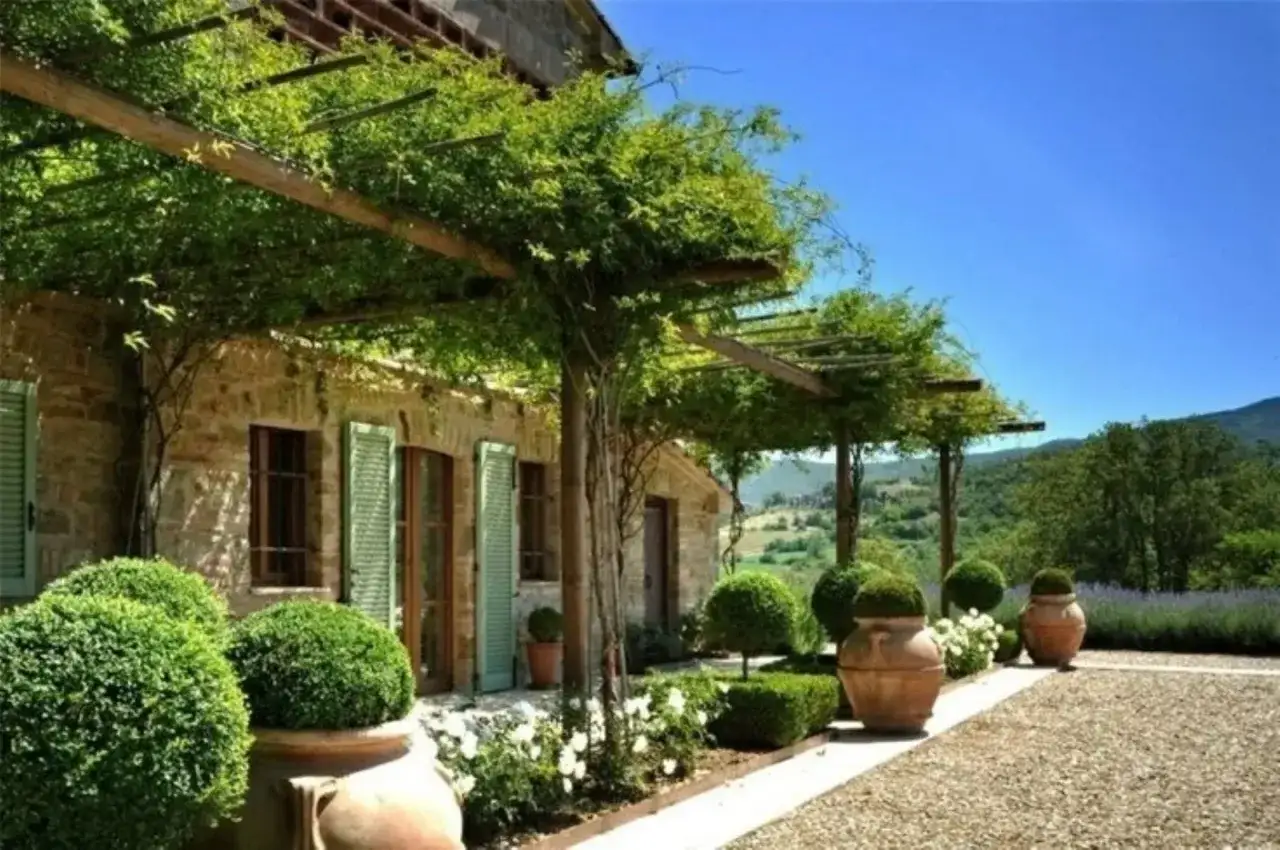 Case in campagna con pergolato verde, vasi in terracotta e vista collinare. Idee per un giardino da sogno.