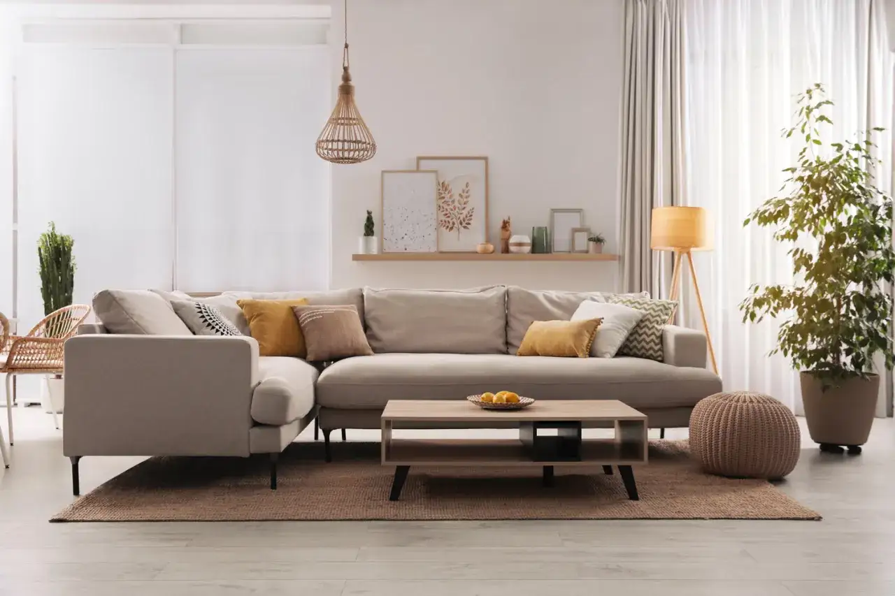 Divano angolare in un caldo colore taupe, con cuscini decorativi e un tavolino in legno.