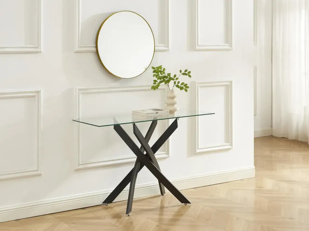 Elegante ingresso casa con specchio rotondo dorato, tavolino in vetro con base nera e decorazioni verdi.