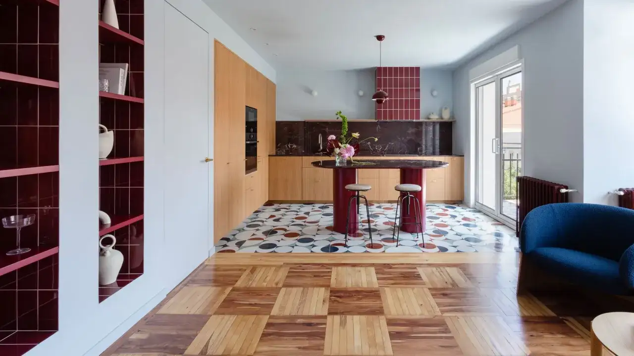 Arredare casa idee: cucina moderna con isola rossa, pavimento a mosaico e parquet. Scaffali a vista con vasi.