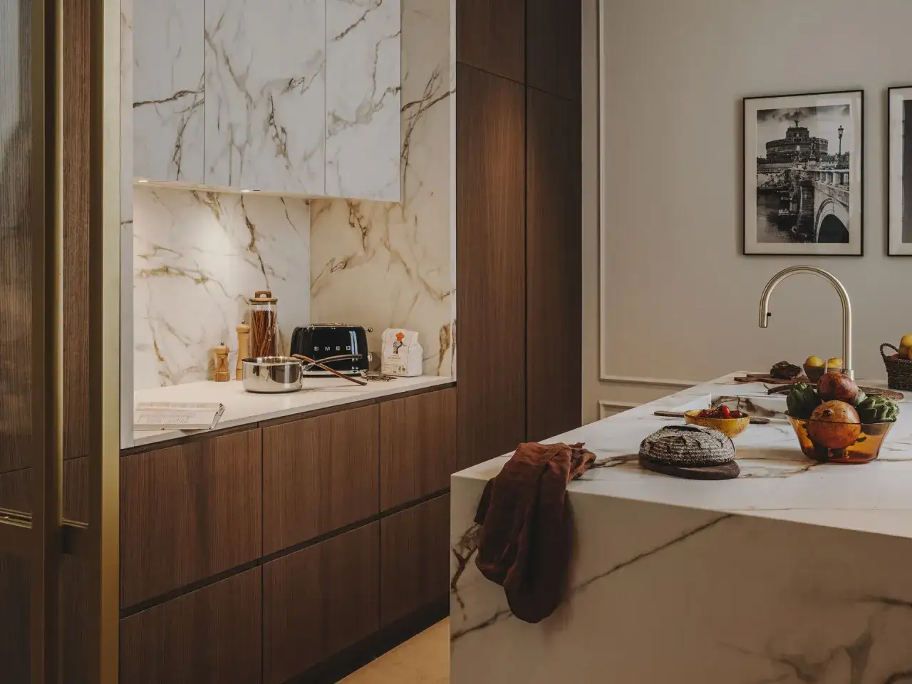 Cucina moderna con marmo e legno scuro, un tostapane Smeg e frutta fresca sull'isola. Un esempio di arredamento contemporaneo chic.