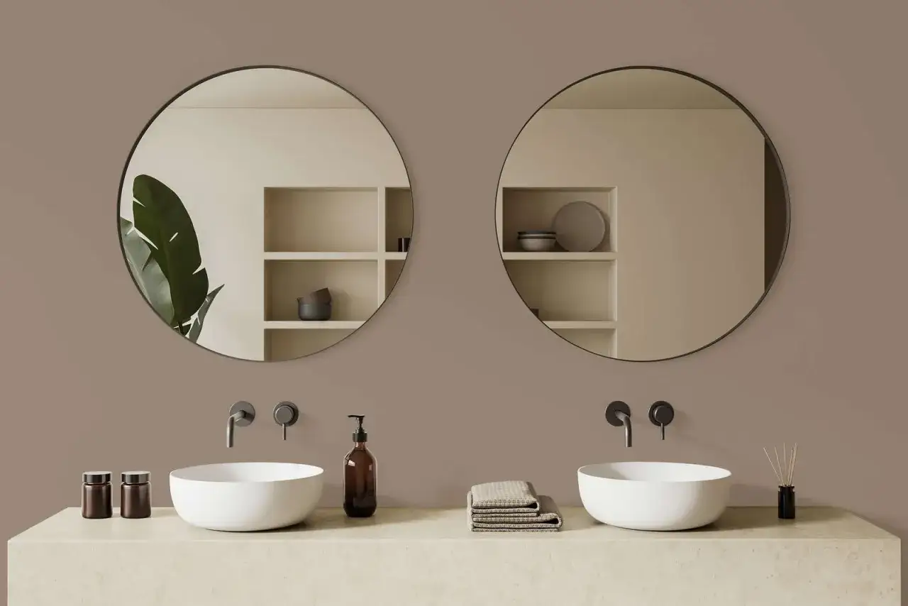 Bagno moderno con lavabi bianchi, specchi rotondi e pareti color taupe.