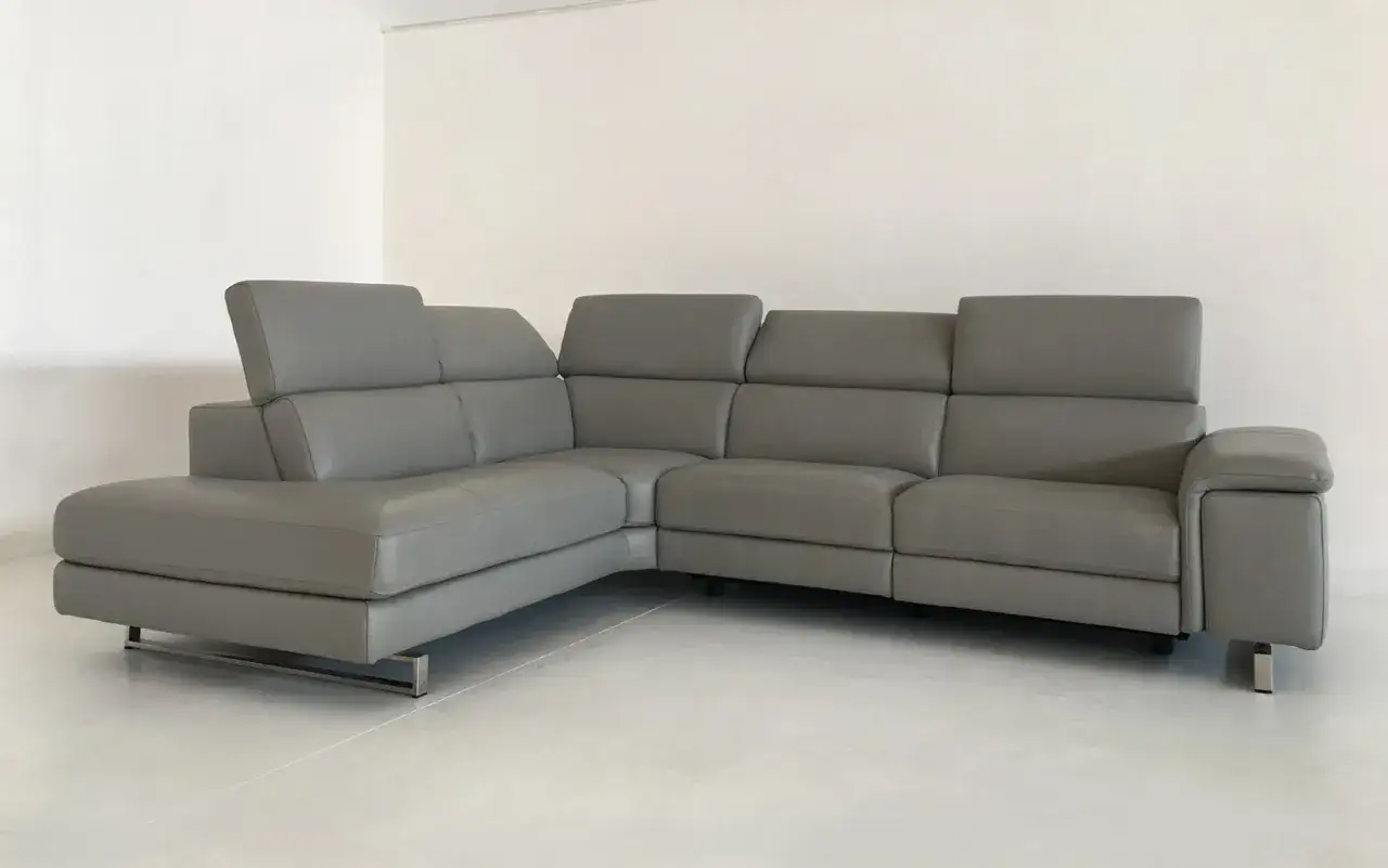 Divano angolare grigio in full grain leather, con poggiatesta regolabili e piedini in metallo.