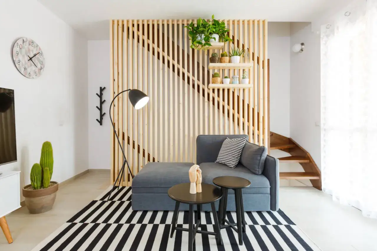 Soggiorno moderno con divano grigio, lampada ad arco e pannello in legno. Un esempio di come illuminare un soggiorno con poca luce, usando luci strategiche e colori chiari.