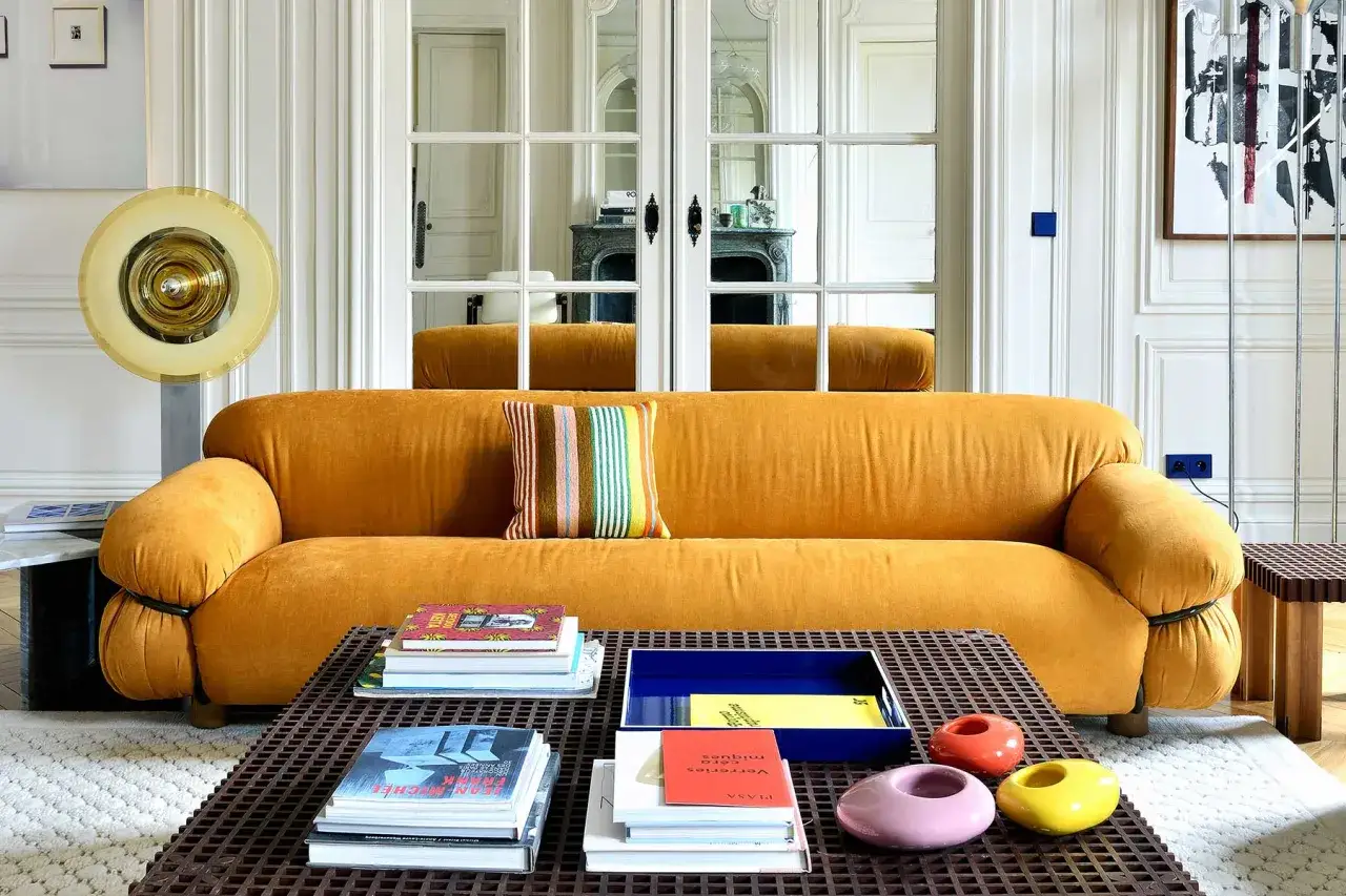 Divano senape abbinamenti: un cuscino a righe colorate e libri sul tavolino creano un look accogliente.