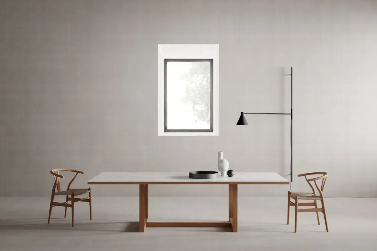Un elegante tavolo minimal design con piano in marmo e struttura in legno, affiancato da due sedie in legno con seduta intrecciata.