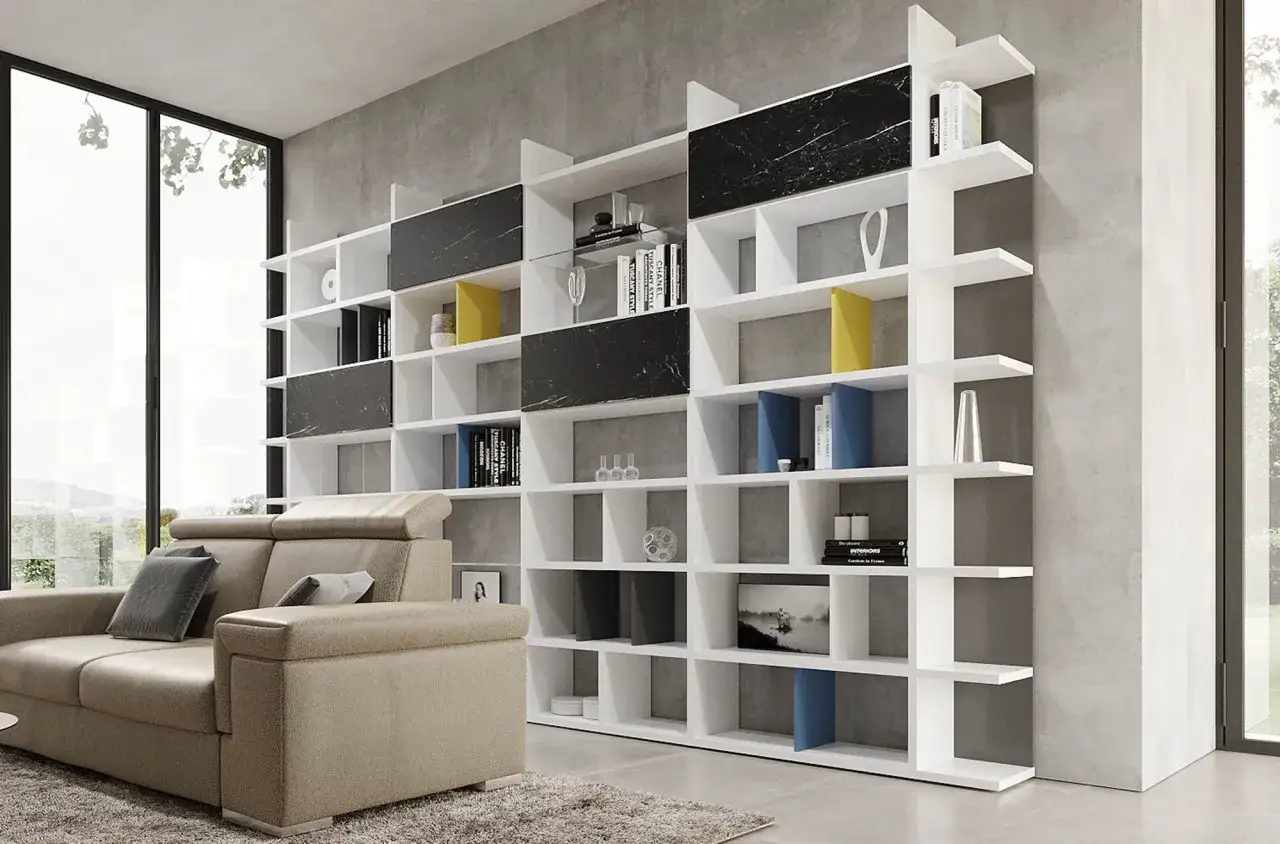 Librerie stravaganti con pannelli effetto marmo nero e ripiani bianchi, piene di libri e oggetti decorativi, accanto a un divano beige.