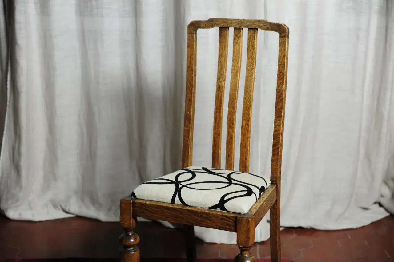 Sedia in legno con schienale a listelli e seduta imbottita con fantasia geometrica. Guida per come rivestire una sedia con schienale.