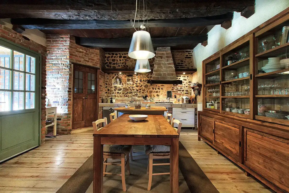 Cucina rustica con tavolo in legno, camino in pietra e credenza. Perfetta per chi cerca idee per una casa in campagna.