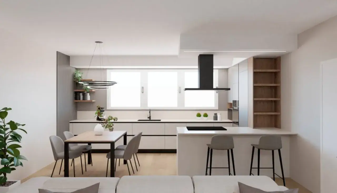 Cucina moderna con isola e tavolo, integrata in un divano open space. Pareti bianche, mobili chiari e dettagli in legno creano un ambiente luminoso e accogliente.