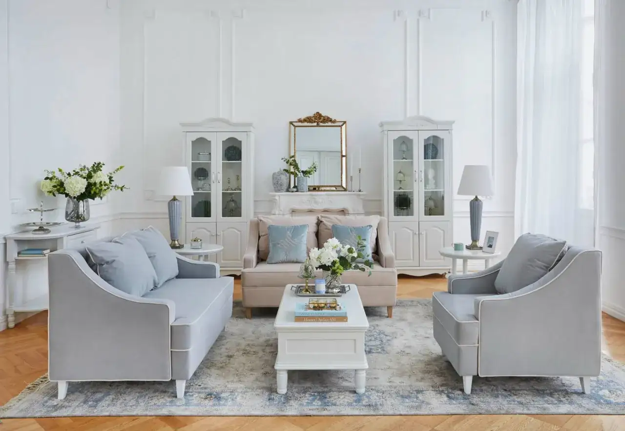 Elegante salotto shabby chic moderno con divani grigi, poltrone, tavolino bianco, specchio dorato e vetrine.