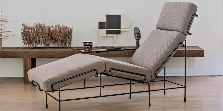 Chaise longue design con struttura in metallo nero e rivestimento in tessuto beige. Un pezzo d'arredo moderno che invita al relax.